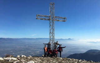 Das Kreuz auf dem Gipfel des Berges mit den jungen Leuten drumherum
