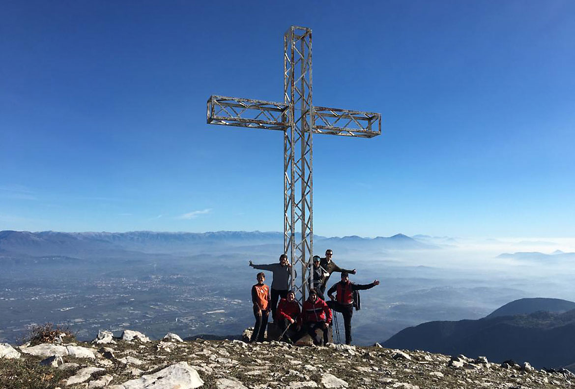 Cross on top of the mountain with young people around